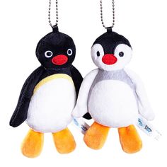 two stuffed penguins hanging from chains on a white background