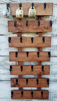 a wooden peg board with black knobs and some coffee cups on the top one