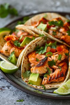 shrimp tacos with avocado and cilantro are served on a plate