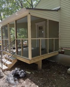 a small house with a screened porch and stairs leading up to the front door area