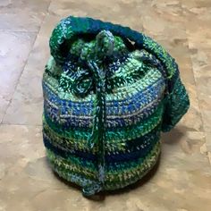 a multicolored crocheted bag sitting on the floor