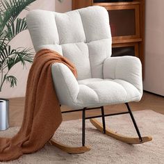 a white rocking chair with a blanket on it