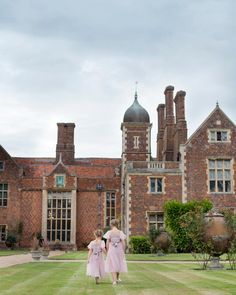 two girls in pink dresses walking towards a large building