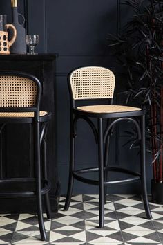 two wicker bar stools next to each other on a checkered tile floor