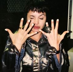 a woman holding her hands up to her face with two fingers in front of her face