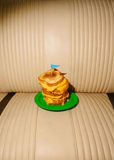 a stack of pancakes sitting on top of a green plate in the back seat of a car