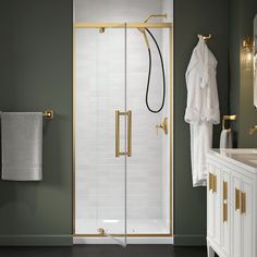 a bathroom with green walls and gold accents on the shower door, towel rack, and sink