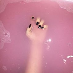 a person's feet with black nail polish in a pink bathtub