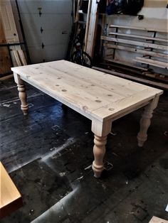 a white table sitting on top of a wooden floor next to a pile of wood