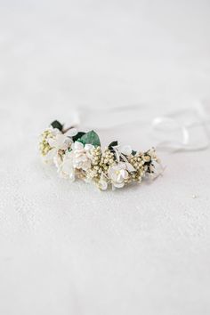 a headband with flowers and leaves on it sitting on a white tableclothed surface