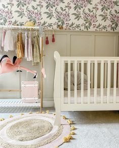 a baby's room with floral wallpaper and pink furniture