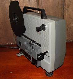 an old style projector sitting on top of a wooden floor next to a wall