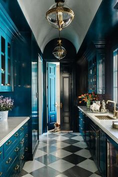 a kitchen with blue cabinets and checkered flooring on the walls, along with a chandelier hanging from the ceiling