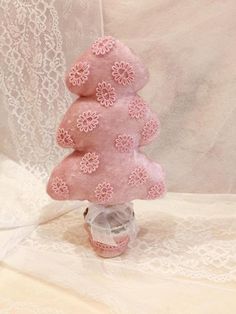 a small pink christmas tree made out of felt and lace on a white tablecloth