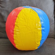 a large colorful ball sitting on top of a gray couch in front of a pillow