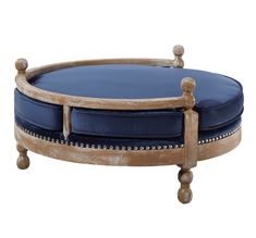 a round wooden ottoman with blue cushions on it's sides and legs, in the shape of an oval footstool