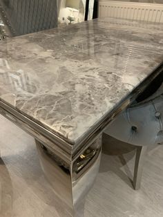 a marble dining table with chrome legs in a showroom or conference room, showing the top and bottom part of the table