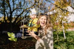 a woman holding a baby on a swing