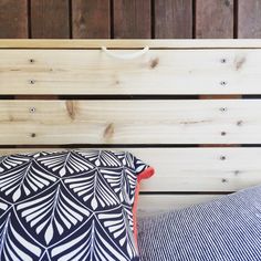 two pillows sitting next to each other on top of a wooden bench with wood slats in the background