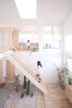 a woman is walking up the stairs in a house with wood floors and white walls