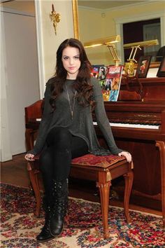 a woman sitting on top of a stool next to a piano