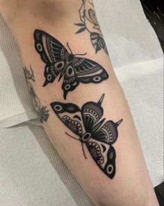 a close up of a person's leg with tattoos on it and moths in the background