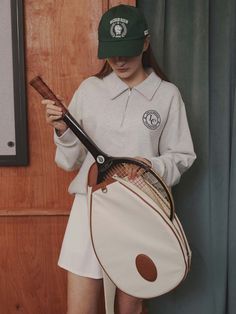 a woman holding a tennis racket and bag