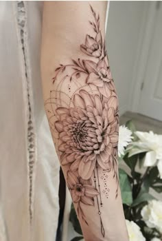 a woman's arm with black and white flowers on the left side of her arm