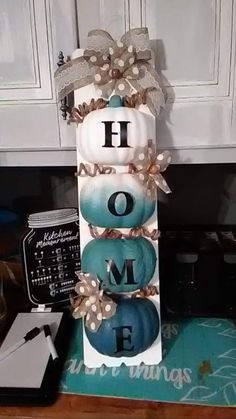 a tall tower with some pumpkins in it on top of a kitchen counter next to a phone