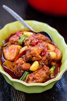 a green bowl filled with meat and vegetables