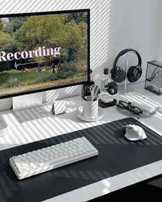 a computer monitor sitting on top of a desk next to a keyboard and headphones