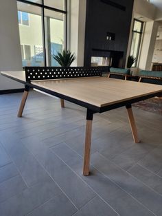 a ping pong table in an office lobby with large windows and potted plants