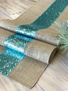 two pieces of burlock fabric with blue sequins on them, sitting on a wood floor