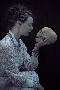 a woman holding a human skull in her hands