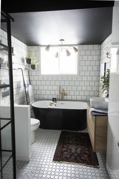 a black and white bath tub sitting next to a toilet under a window in a bathroom