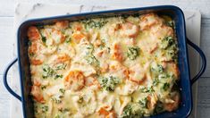 a casserole dish with shrimp, broccoli and cheese in it on a white table