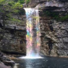 there is a waterfall that has colored lights on it's side and water below