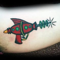 a tattoo with a red and green rocket ship on the side of her leg,