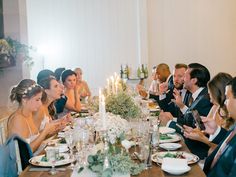 a group of people sitting around a table with plates and glasses on it, all dressed in formal wear