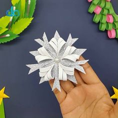 someone is holding an origami snowflake in their hand, surrounded by paper stars