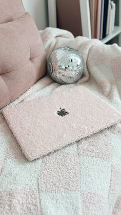 a bed with a pink comforter and a disco ball on it's side