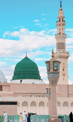 two men standing in front of a building with a green dome on top and white walls