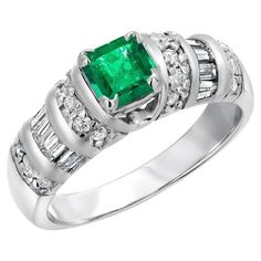 an emerald and diamond ring set in 18k white gold with baguets on the shoulders