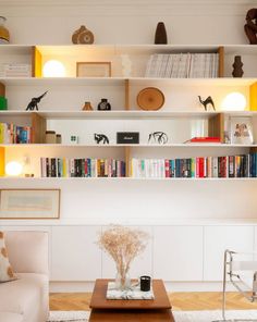 a living room filled with furniture and lots of books on the shelves above it is a coffee table