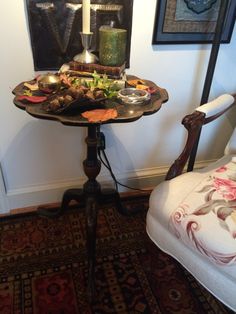 a small table with food on it in front of a chair and wall hangings