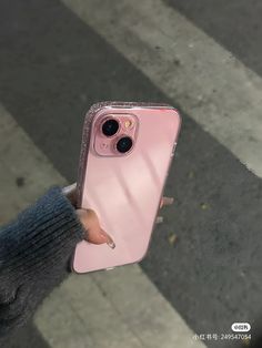 a person holding up a pink phone case on the street with their finger in it