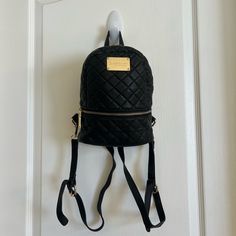 a black backpack hanging on a door with a name tag attached to the front pocket