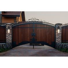 an iron and wood gate in front of a brick house with two lamps on each side