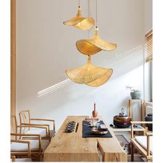 three lights hanging from the ceiling above a table with chairs and other items on it