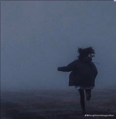 a person running in the fog with an umbrella